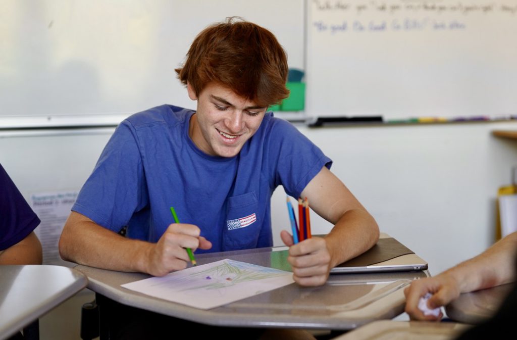 Student writing at desk