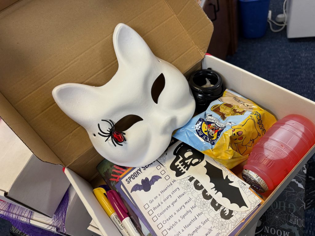 Box filled with assorted snacks and pens and a mask like a rabbit