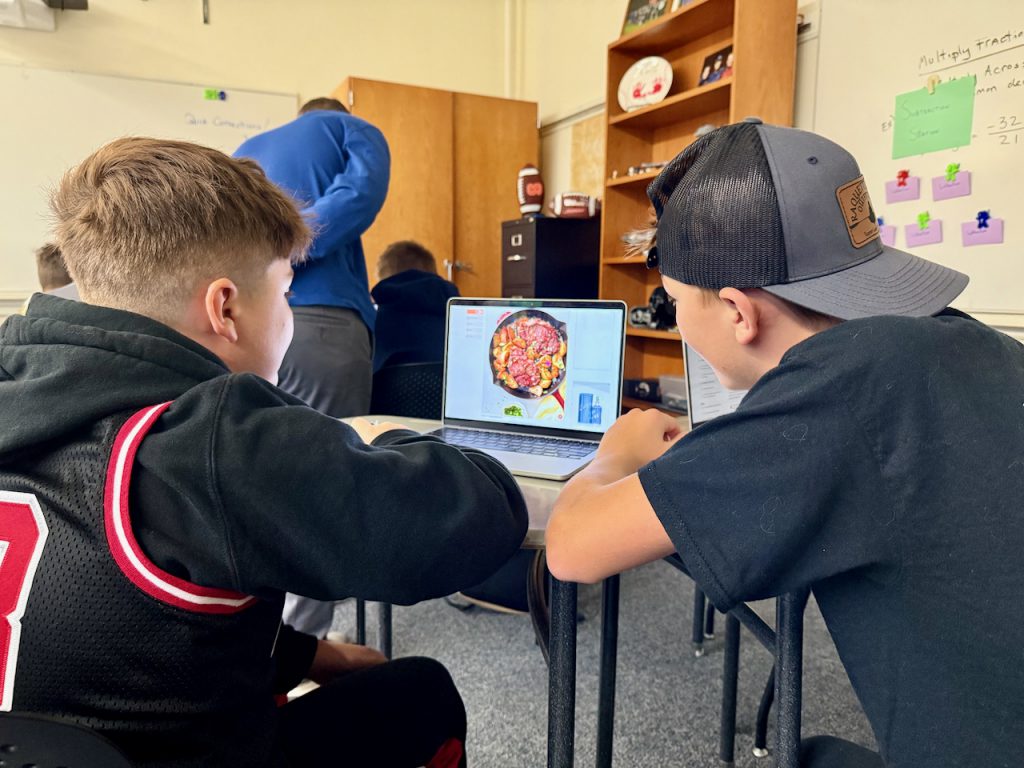 Two students looking at a recipe on a laptop