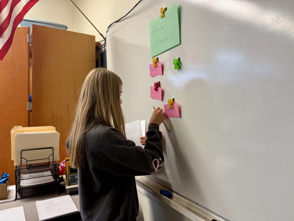 Student taking an index card off of a whiteboard