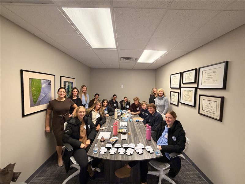 students and adults around a desk with items on it