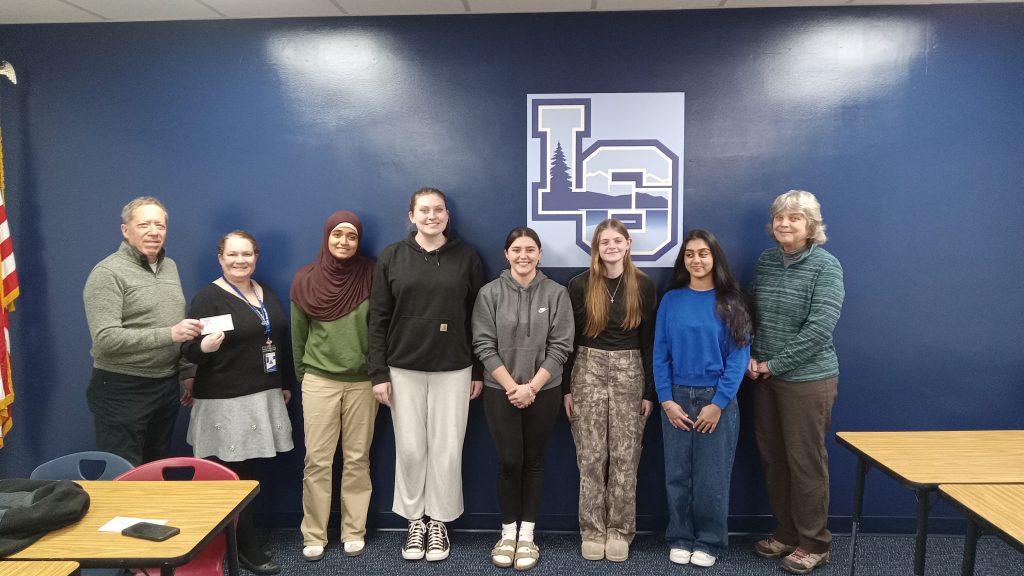 students and two adults standing against a blue wall