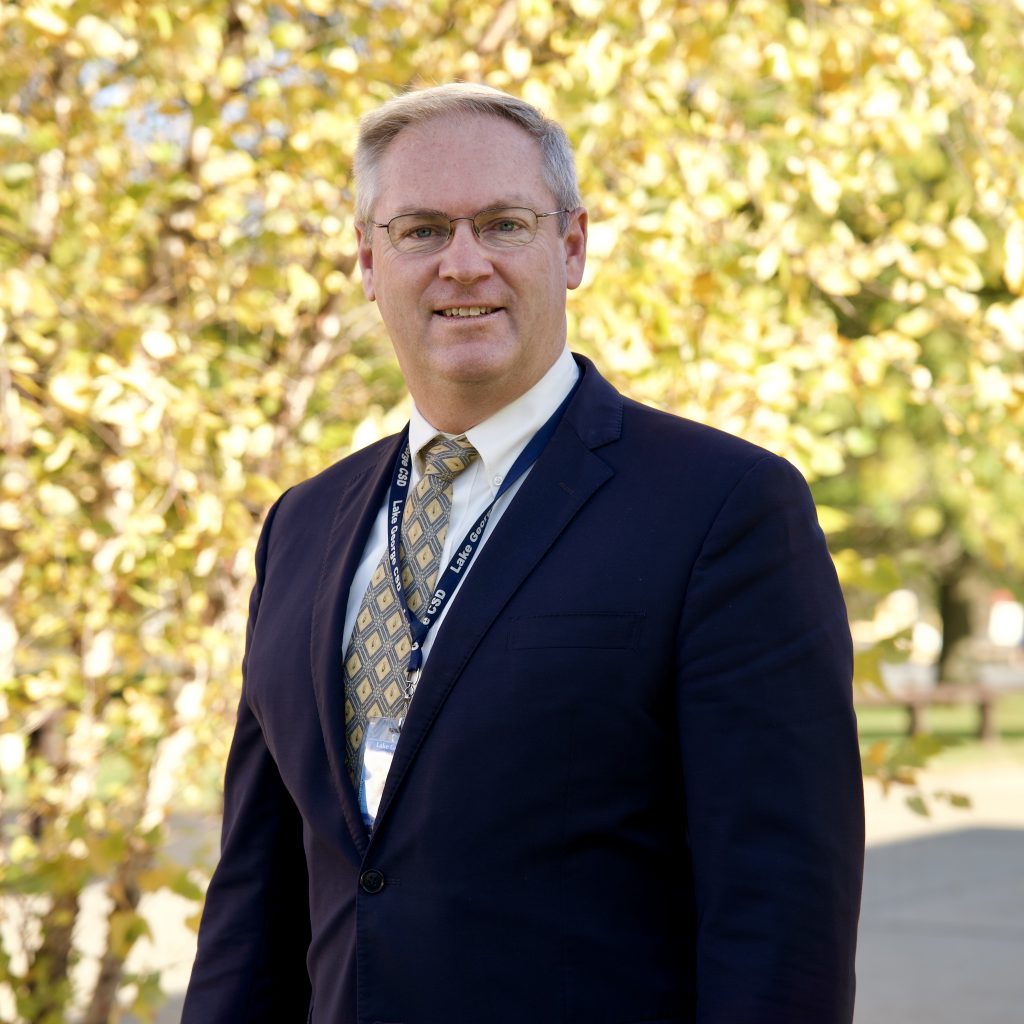 man in suit in front of colorful trees