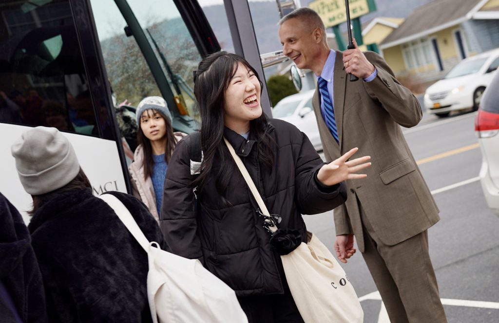 student smiling walking off of a bus