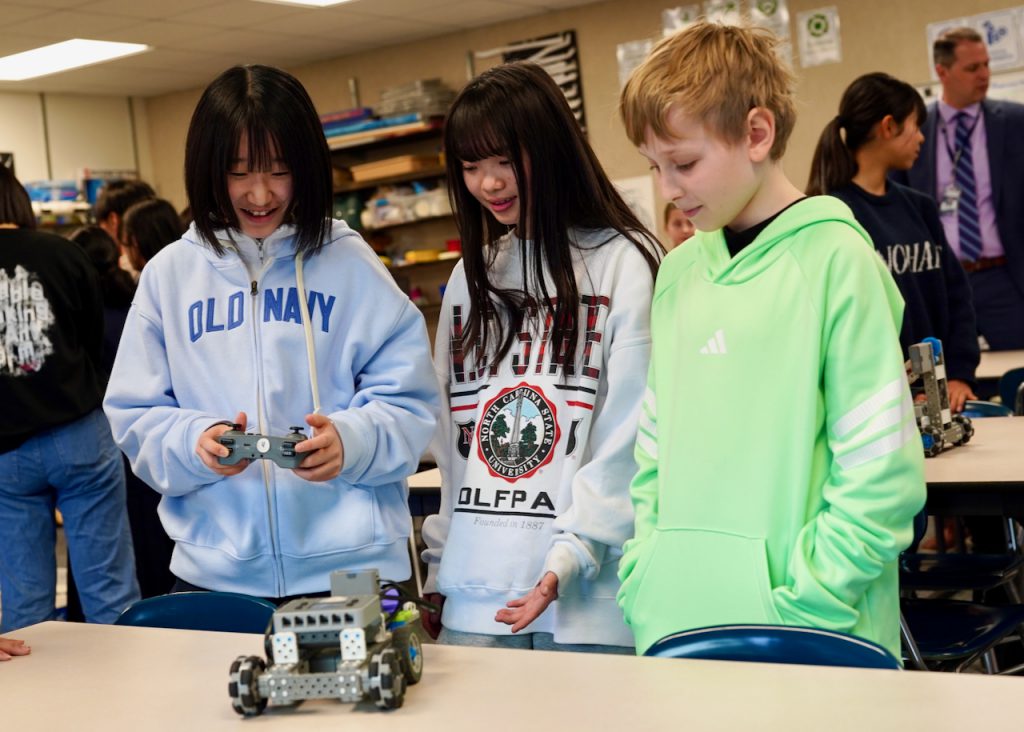 three students using vex robotic cards