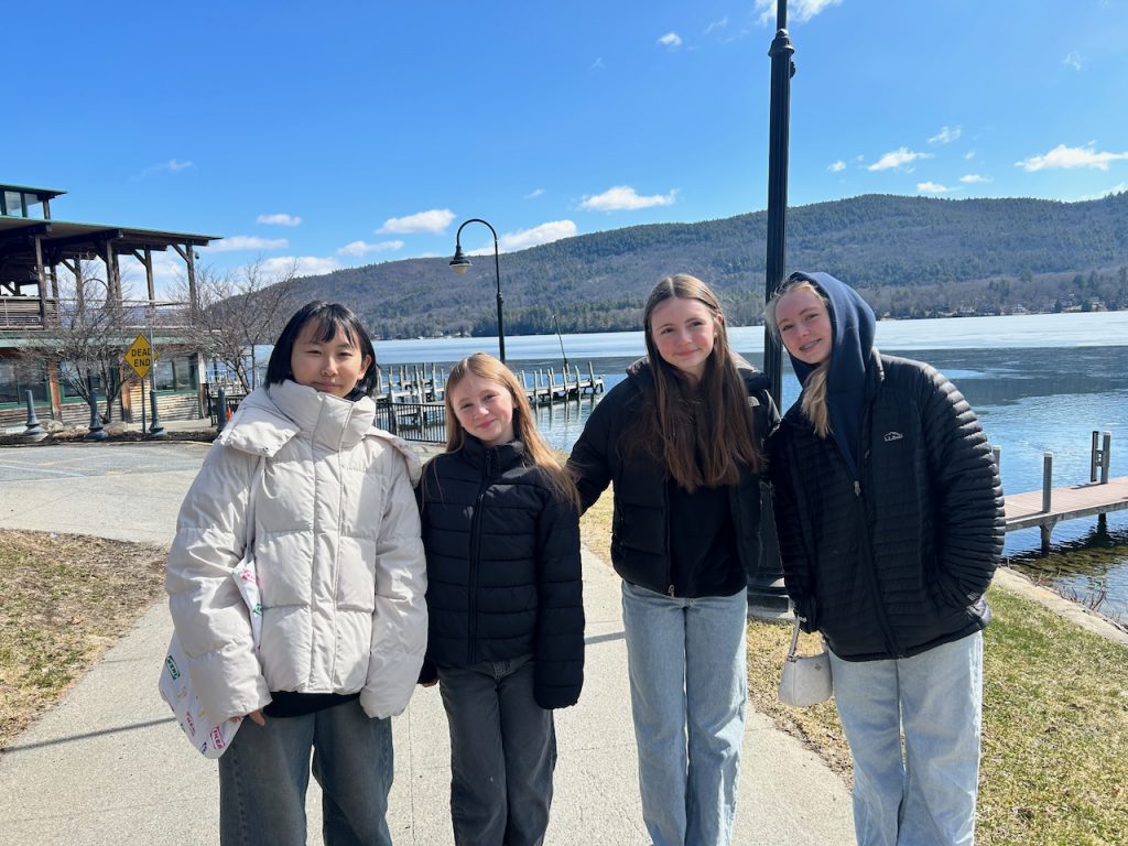 four students standing in front of a lake with docks in the background