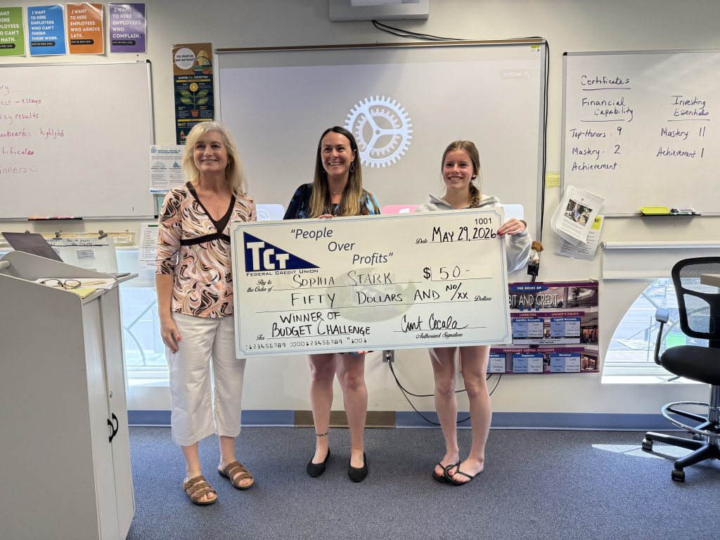 Three women holding a large check with the amount of $50 written on it