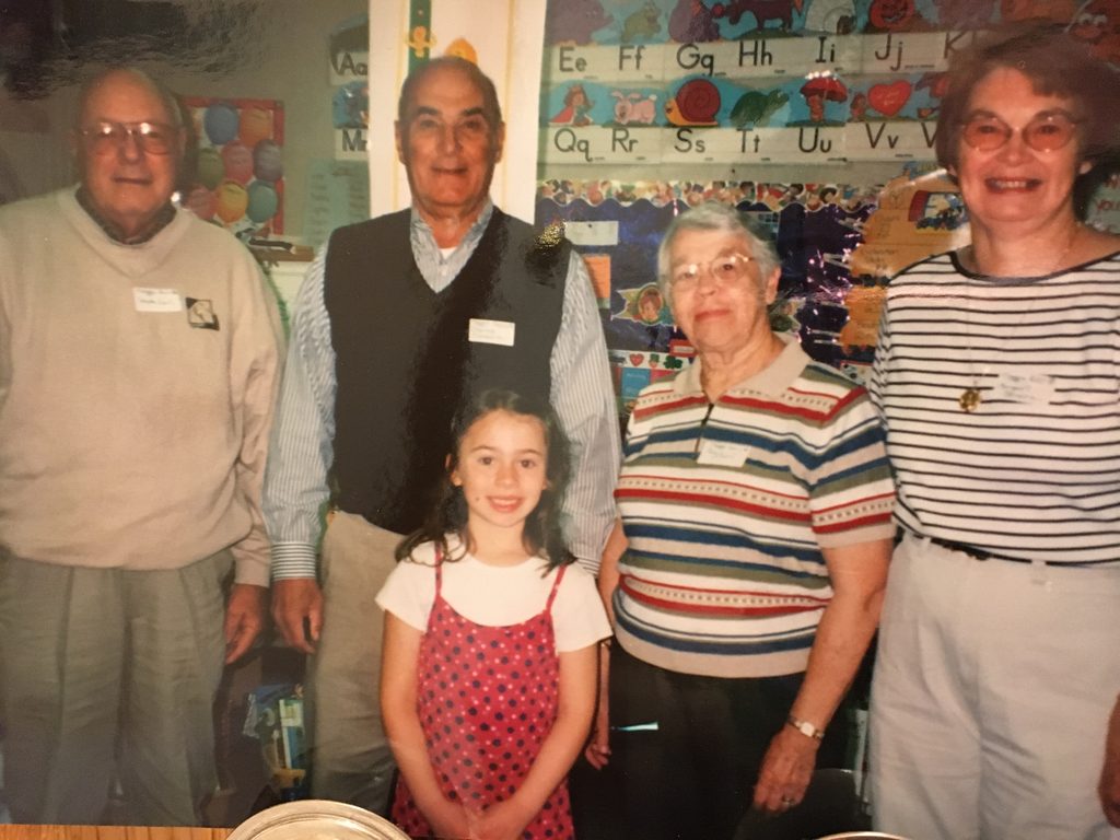Four adults standing with a young girl in a red dress
