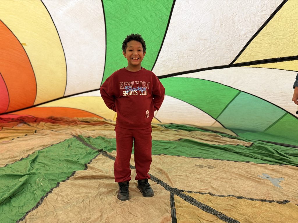 A student standing inside a colorful hot air balloon smiling at the camera