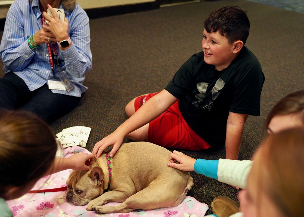 student petting dog on floor